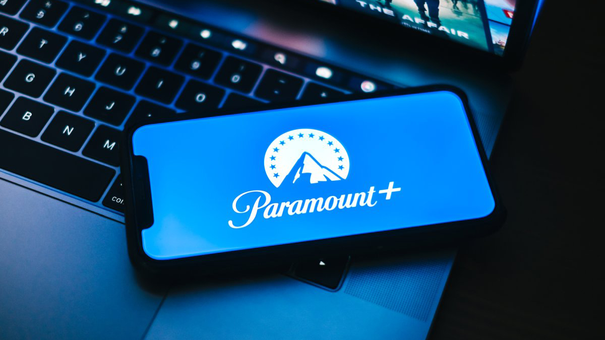 Image of the Paramount Plus logo on a mobile phone resting on a laptop
